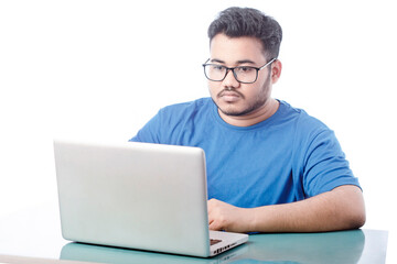 Studio shot of a handsome young boy using a laptop and wearing glass against a white background