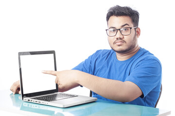 young man showing blank white laptop screen and pointing finger