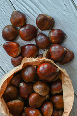 Chestnuts in a paper bag on a wooden background
