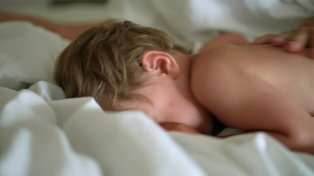Mother and child in morning bed together waking up boy