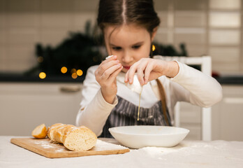 Fototapeta na wymiar Home cooking. A little girl cooks bread dough at home in the kitchen.