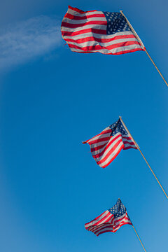 Three American flags against a blue sky.