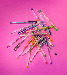 A set of colorful gel pens close-up on a pink background