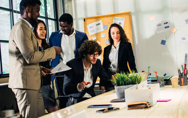 Diverse and multiracial smart businesspeople wearing formal suits, using computer, working, meeting, brainstorming together about company marketing plan or creative idea in indoor modern office.