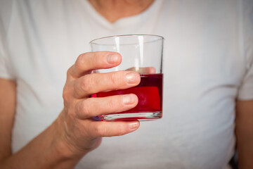 Senior woman (old lady) with a glass of juice. An elderly lady and her hands.