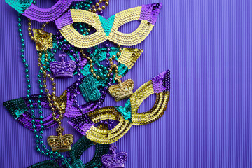 Frame of Mardi gras, venetian or carnivale mask and beads on a purple background