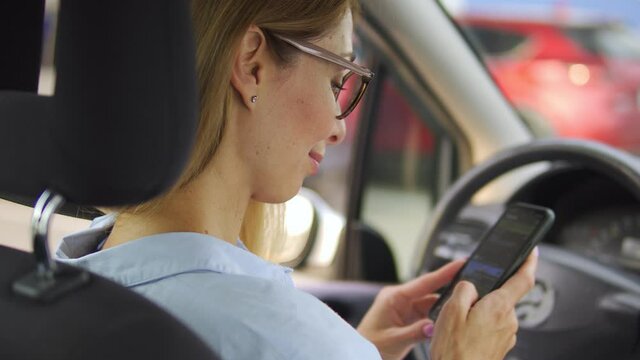 Attractive woman in eyeglasses smiling scrolling social networks on smartphone