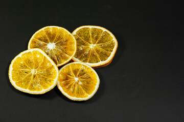 Fototapeta na wymiar Decorative orange slices lie on a black matte surface. Still life on a black table. 
