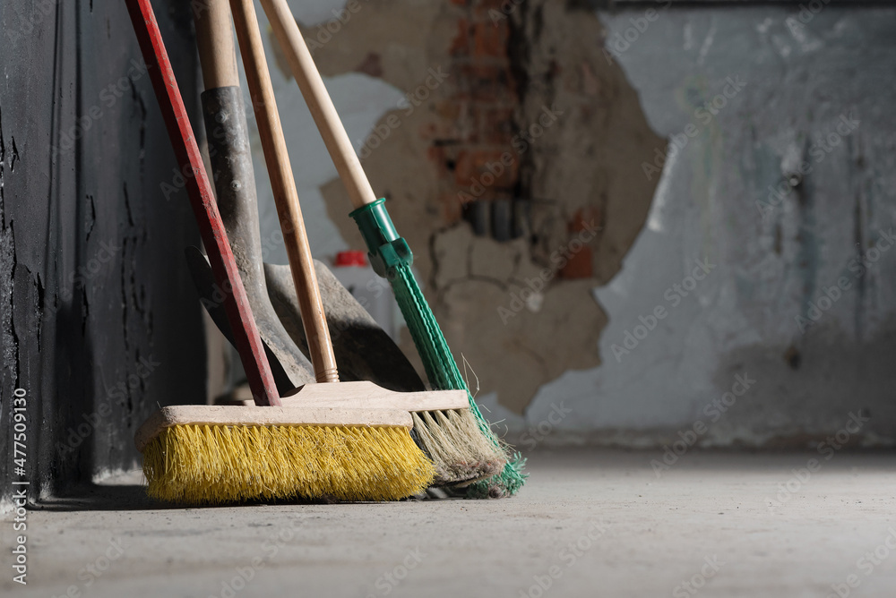 Wall mural Broom on the dusty floor on the black wall background.