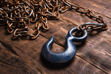 Obraz premium Construction hook on the chain on the wooden workbench background.