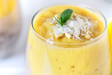 Delicious mango and chia pudding in a glass on the white ceramic tile table close up. Healthy morning breakfast concept