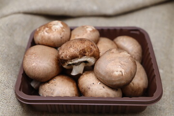 Large brown raw mushrooms royal champignons in a tray on burlap