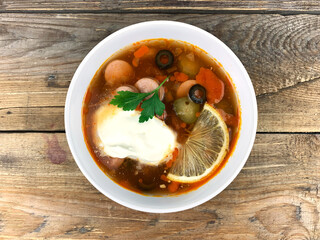 Traditional russian meat soup Solyanka in a bowl on wooden background