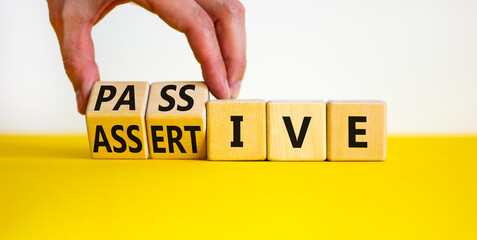 Passive or assertive symbol. Businessman turns wooden cubes and changes the word passive to...