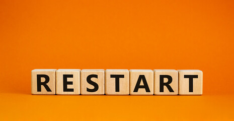 Restart and start symbol. The concept word Restart on wooden cubes. Beautiful orange table, orange background, copy space. Business restart and start concept. - obrazy, fototapety, plakaty