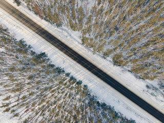 Aerial drone view of road in idyllic winter landscape. Street running through the nature from a birds eye view.
