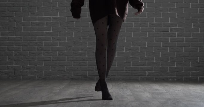 Silhouette of beautiful young woman against brick wall