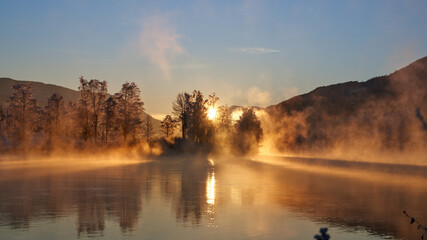 Sunrise over the river Hallingdalselva. Shot at Nesbyen, Norway. It is December and minus 20 degree outside. The water in the river is warmer than the air so therefor the smoke on the river. Frost. 