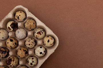 Obraz premium Quail eggs in eco package made of recycled paper, top view. Brown background, copy space
