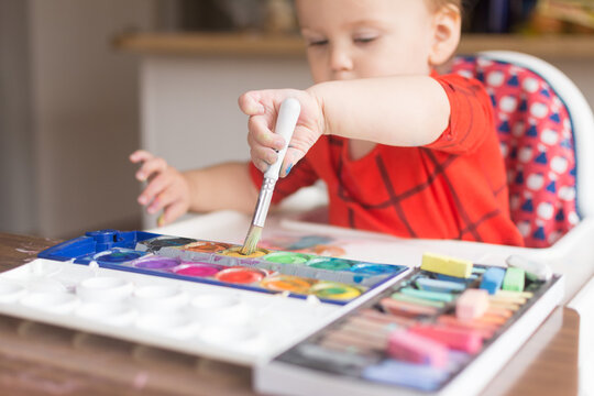 18 month old toddler painting with watercolors independently; grasps paint brush with one hand