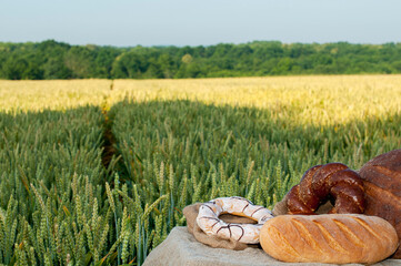 Fresh bread, pastries on a background of wheat field. Clear sunny day