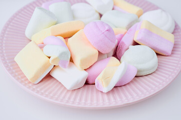 pastel colored marshmallows on a purple plate, close up color photo