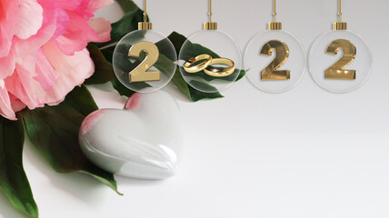 golden wedding rings glass bauble 2022 digits beautiful pink flower on green leaf and white glossy...