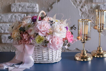 Beautiful bouquet of flowers in basket on blue table. Wicker basket whit preserved flowers. Floristry concept.