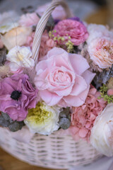 Beautiful bouquet of flowers in basket, woman hands. Wicker basket with preserved flowers. Floristry concept. Spring colors.