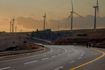 road going into the distance at sunset, windmills along the road