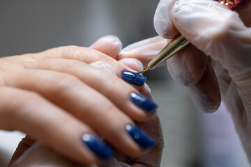 a close-up of the master applies a gel polish with a brush to the surface of the nail under the lamp glowing on them