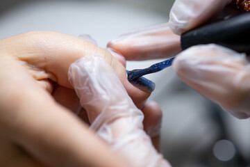 macro photography procedural the master applies gel polish to the nail distributing it with a brush on the surface