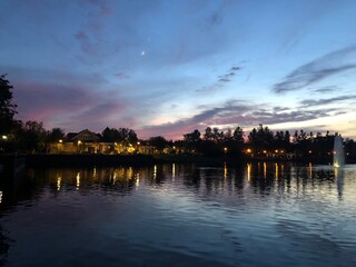 Lake house lights reflecting in the water with pastel clouds and sky.