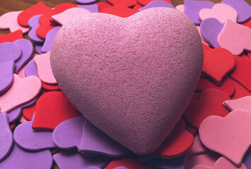 Big pink heart. Around him are scattered small multi-colored hearts. Symbol of Valentine's Day and lovers.