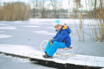 Child with a sled on a frozen lake. Dangerous fun on thin ice in winter.