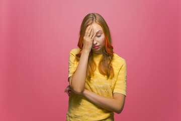 Facepalm gesture. Young woman covering face with hand, feeling shame, disappointment on pink studio background