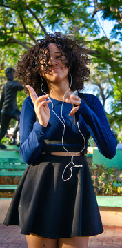 Girl goes out to the park with her cell phone, takes photos and listens to music.