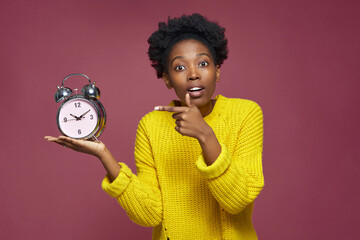 Hot deadline. Stressed worried young african american girl holding alarm clock pointing on...