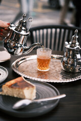Fototapeta na wymiar Woman serving tea on the terrace of an arabic teahouse. Accompanied with a cheese cake