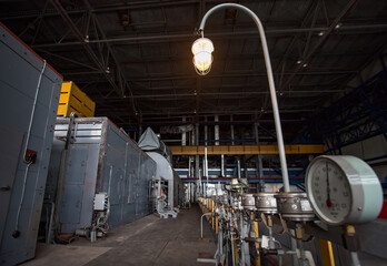 Machine room of heat power station. Grey generator machine left. Emergency lamp right. Manometers...