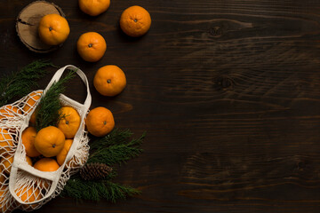 Fresh mandarin oranges fruit or tangerines on a wooden table. Christmas composition. Mandarin oranges in organic cotton mesh bag. Grocery shopping fabric net bag. No plastic bag. - 477521759