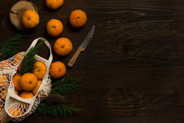 Fresh mandarin oranges fruit or tangerines on a wooden table. Christmas composition. Mandarin oranges in organic cotton mesh bag. Grocery shopping fabric net bag. No plastic bag. - 477521768