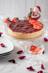 Whole strawberry cheesecake on the Christmas table. With dolls, and crystal accessories and decoration that reminds Christmas