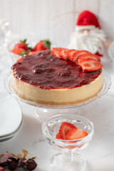 Whole strawberry cheesecake on the Christmas table. With dolls, and crystal accessories and decoration that reminds Christmas