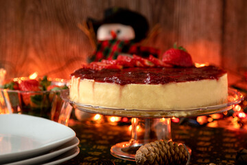 Whole strawberry cheesecake on the Christmas table. With dolls, lights and decorations that remind you of Christmas