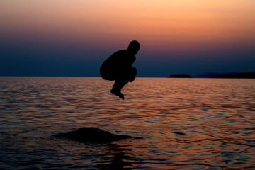 Young man in the air jumping in the sea © Jelena