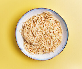  Plate of white spaghetti over yellow background