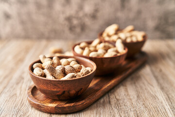  Bowls of peanuts with shell on a wooden surface