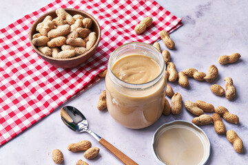  Bowl of peanuts with shell and peanut butter cream on a marble surface