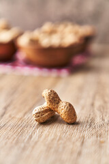  Two peanuts with shell on a wooden surface